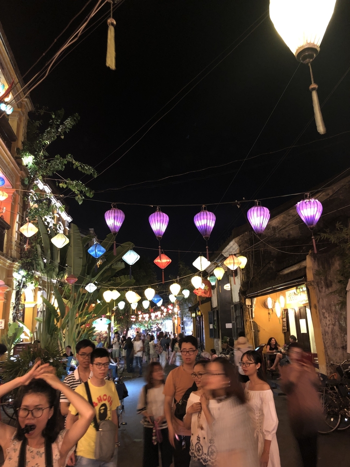 Des lanternes colorées suspendues au-dessus d'une rue animée avec une architecture traditionnelle.
