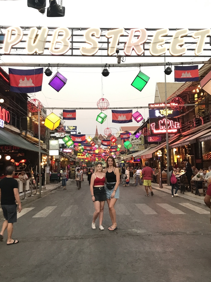 Deux femmes posant sous des décorations de rue colorées.