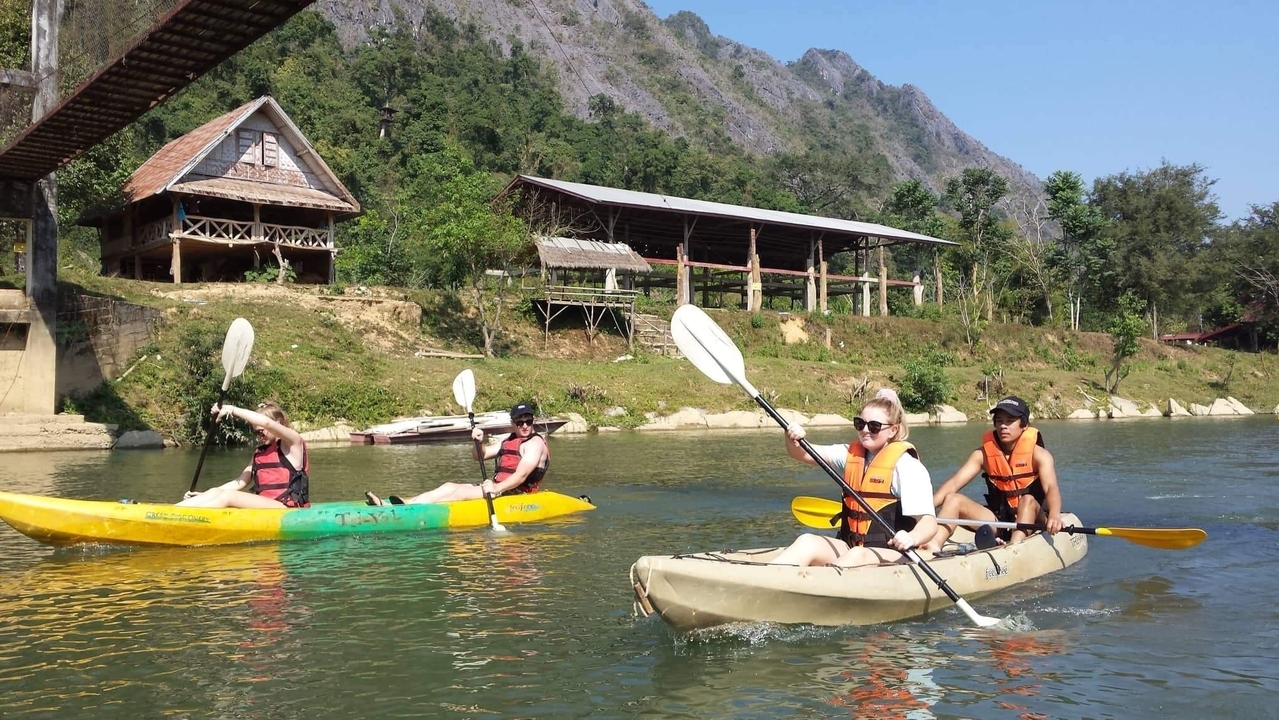 Des gens faisant du kayak sur une rivière calme entourée de montagnes.
