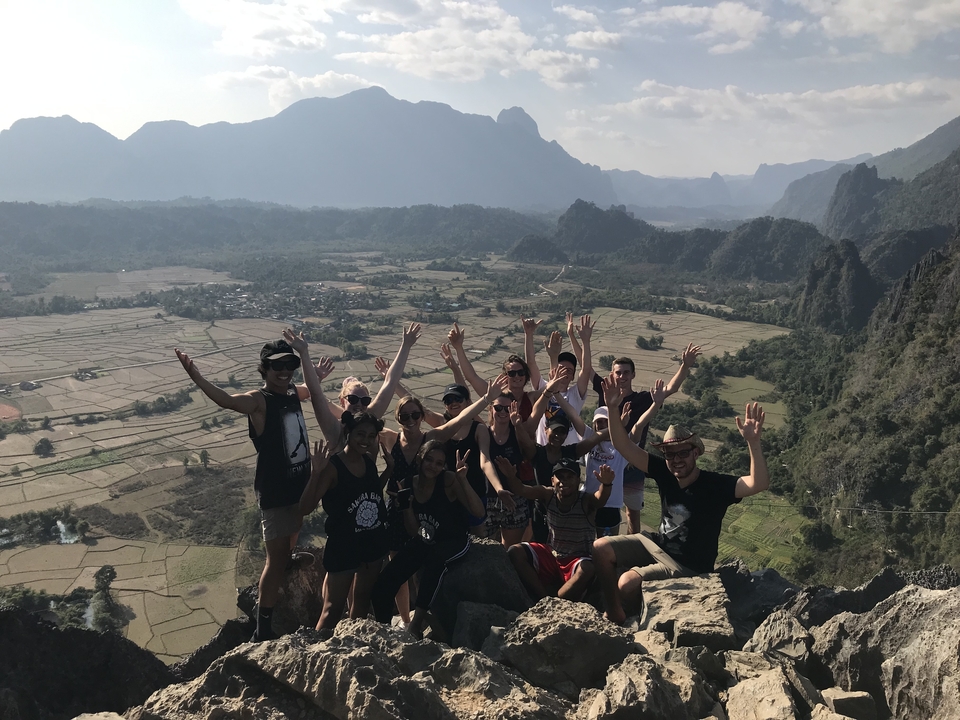 Un grand groupe de personnes qui célèbrent sur une falaise avec des vues panoramiques.