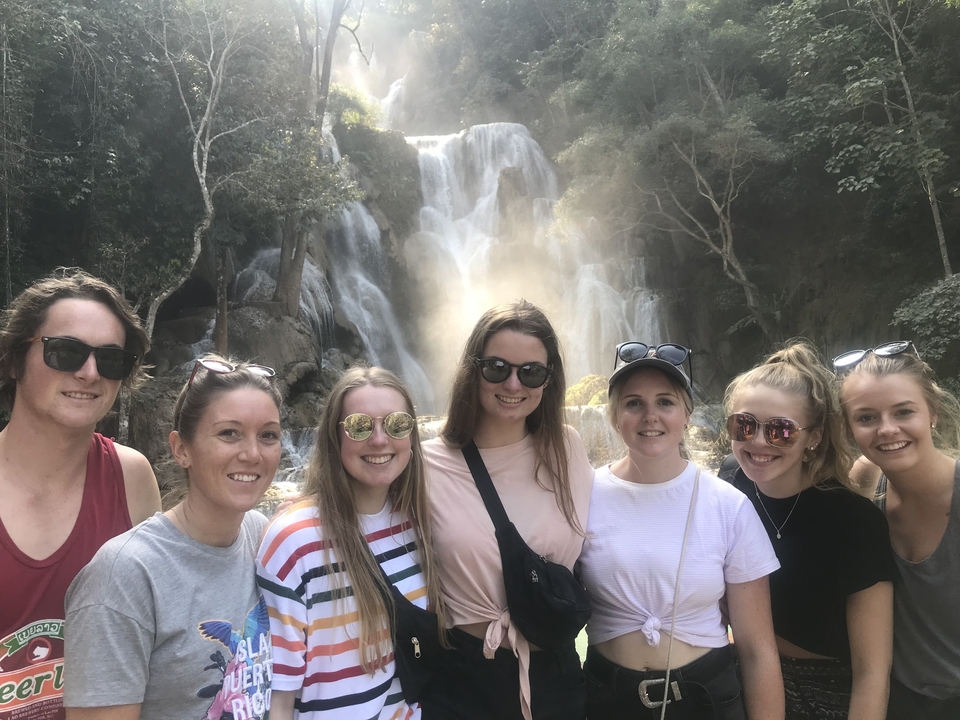 Groupe posant devant une cascade.