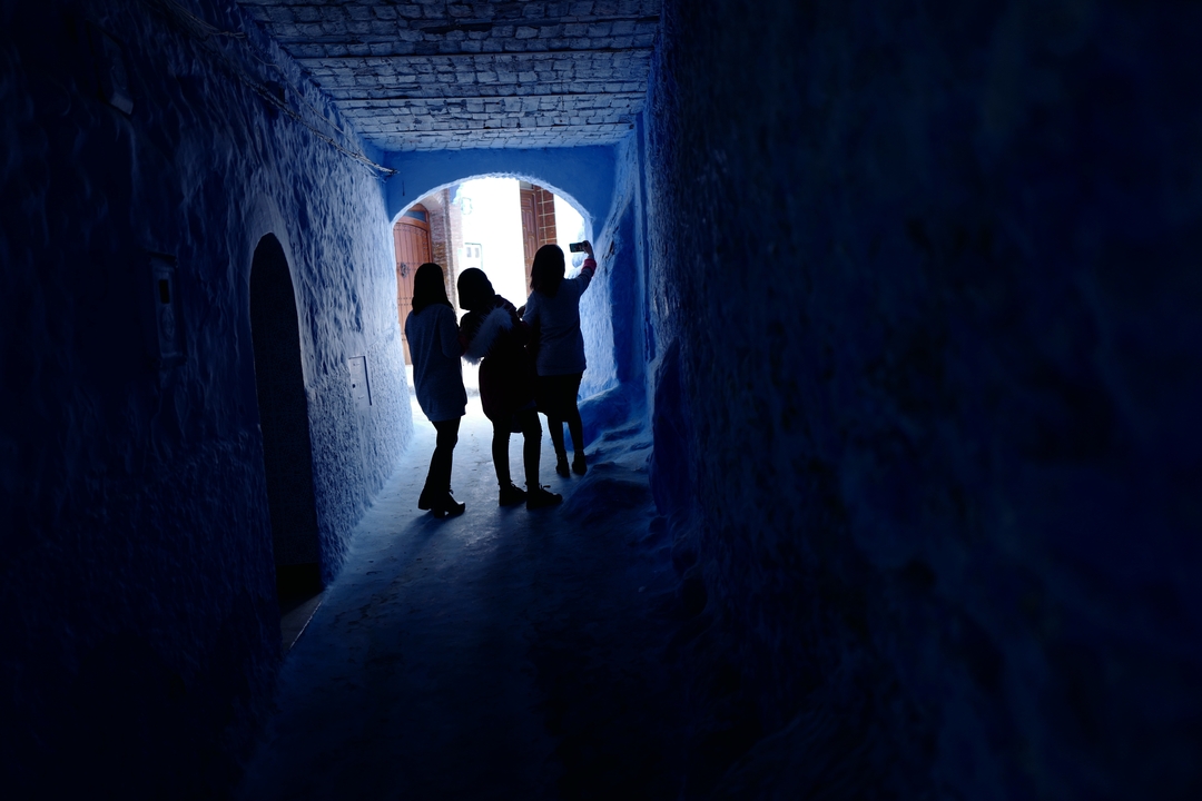 Des personnes en silhouette marchant dans un passage de couleur bleue.
