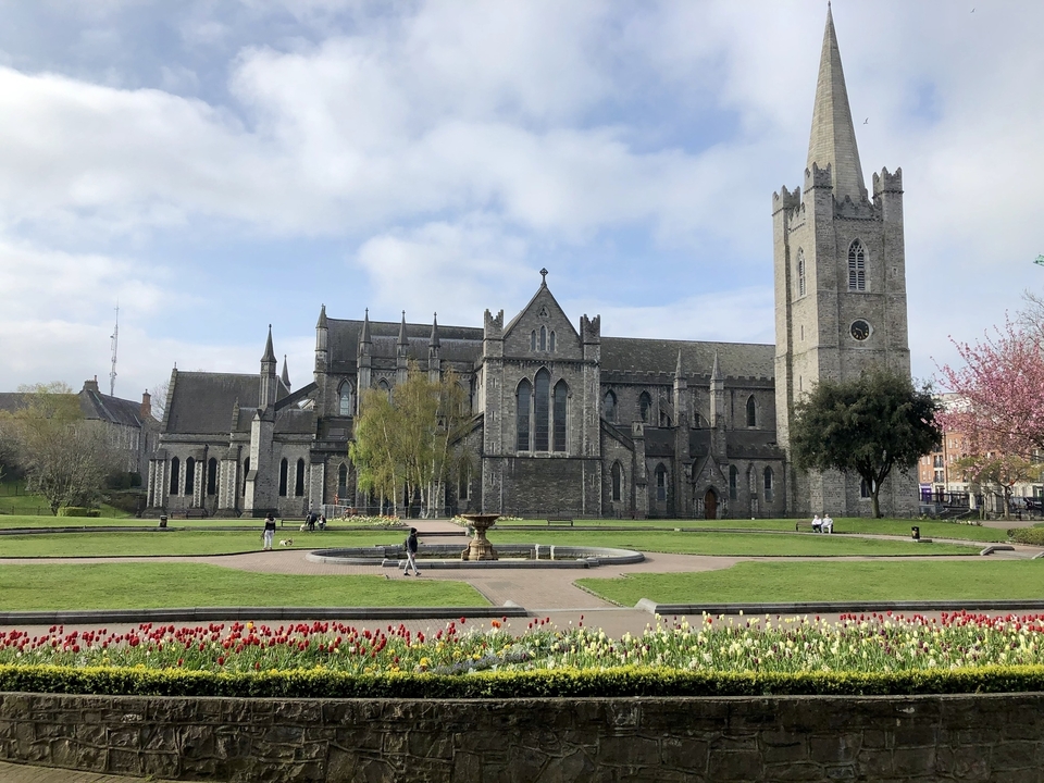 Cathédrale gothique avec une grande pelouse et des parterres de fleurs devant.