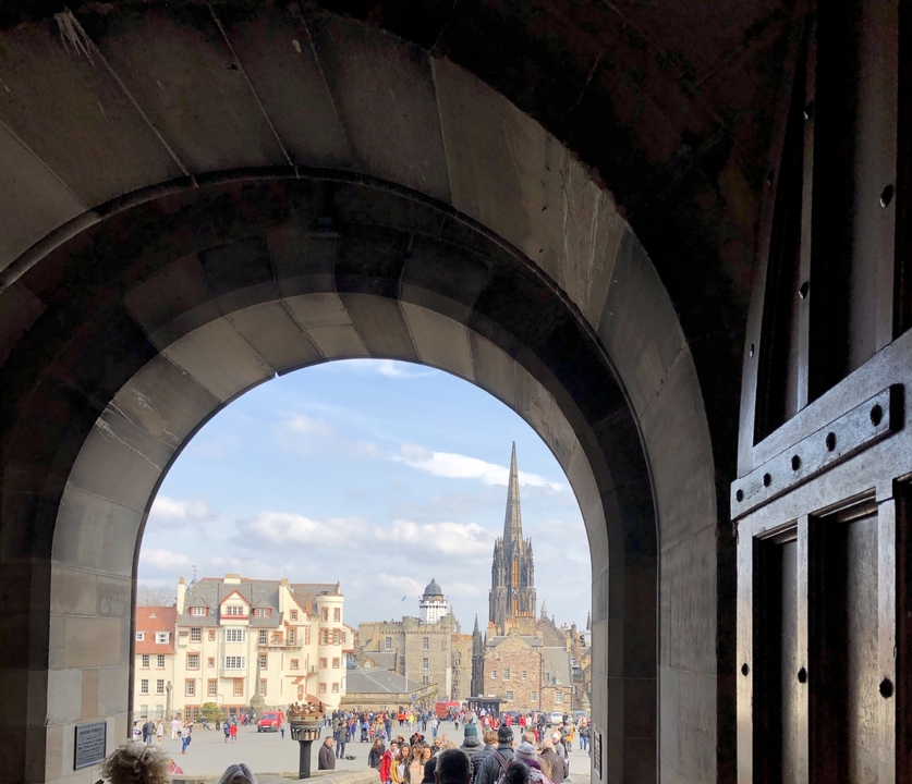 Vue à travers une arcade sur un paysage urbain avec une haute flèche au loin.