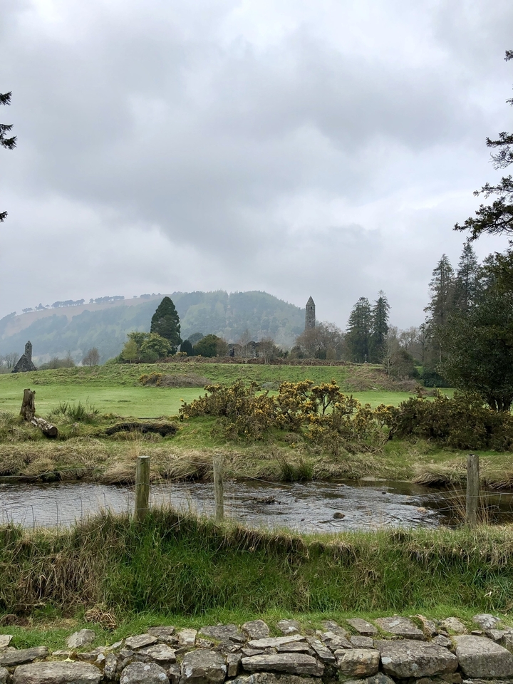 Paysage avec une végétation luxuriante et des structures anciennes au loin.