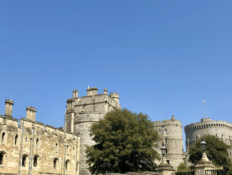 Windsor Castle with round towers and battlements under a blue sky.
