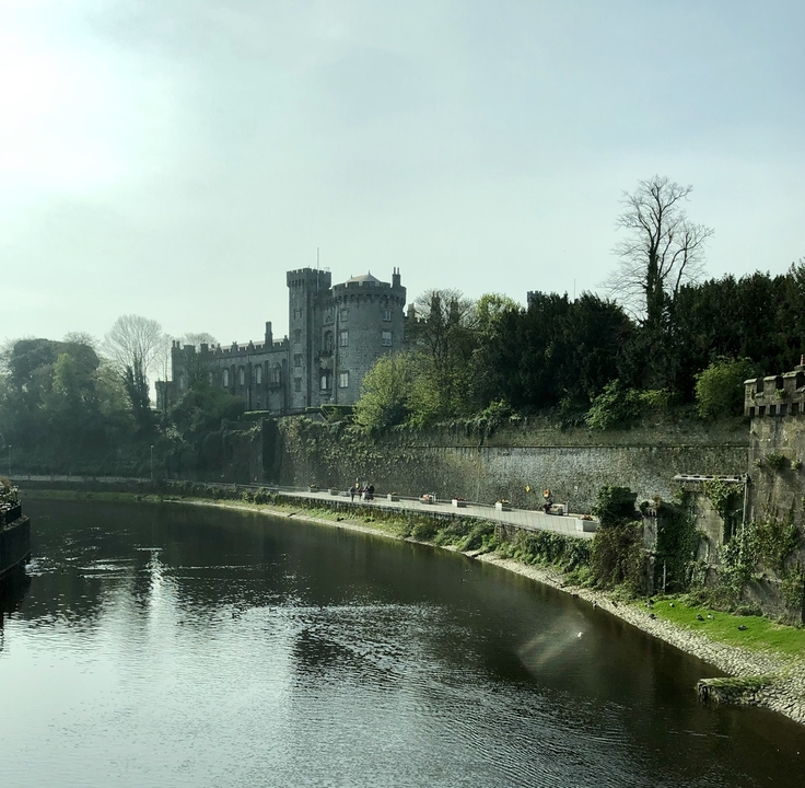 Château sur une berge entouré de verdure.