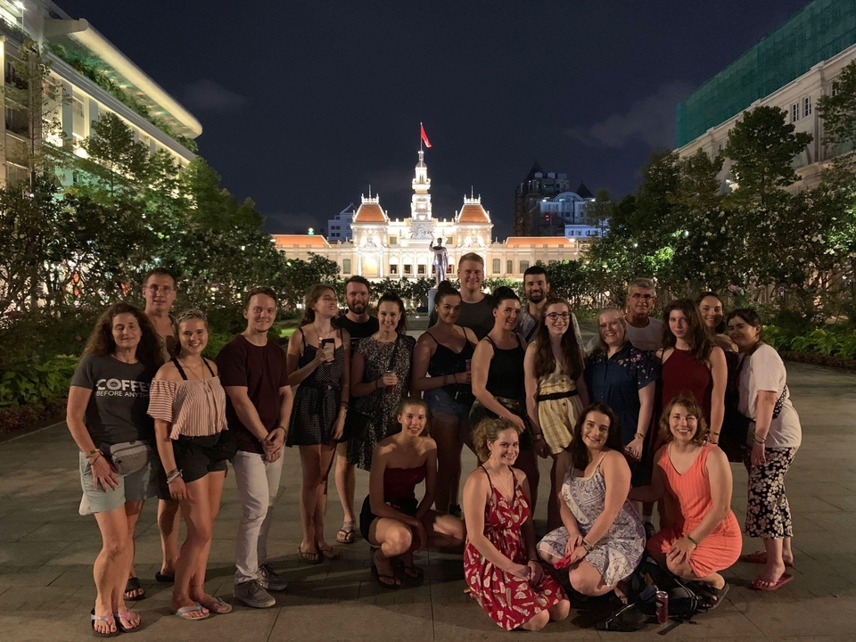Grand groupe posant avec un bâtiment illuminé en arrière-plan.