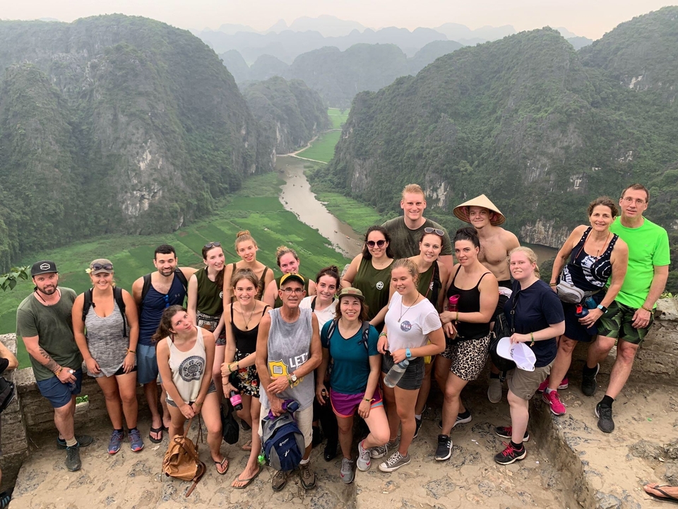 Group posing on a viewpoint with a river and mountains.