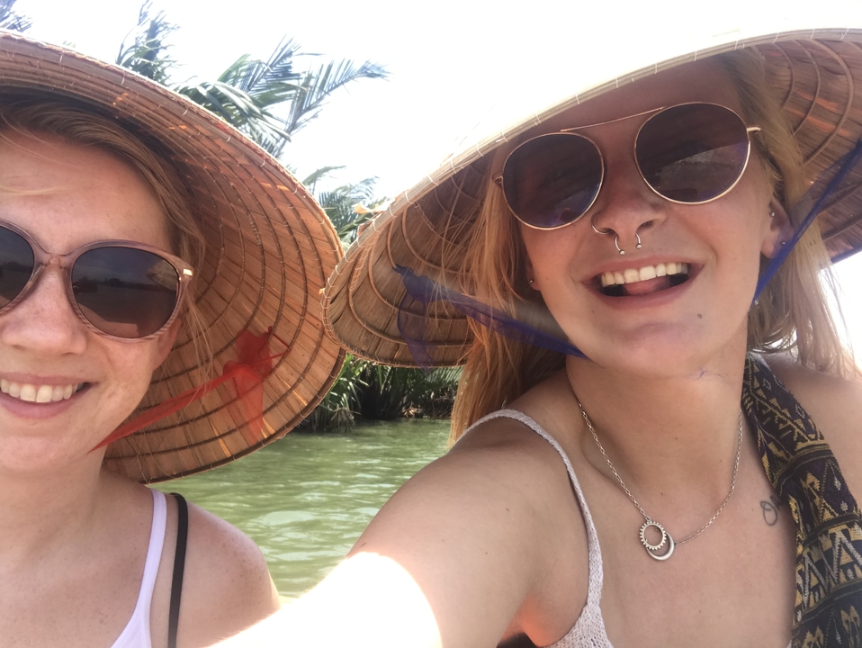 Deux femmes portant des chapeaux de soleil et des lunettes de soleil souriant sur un bateau.