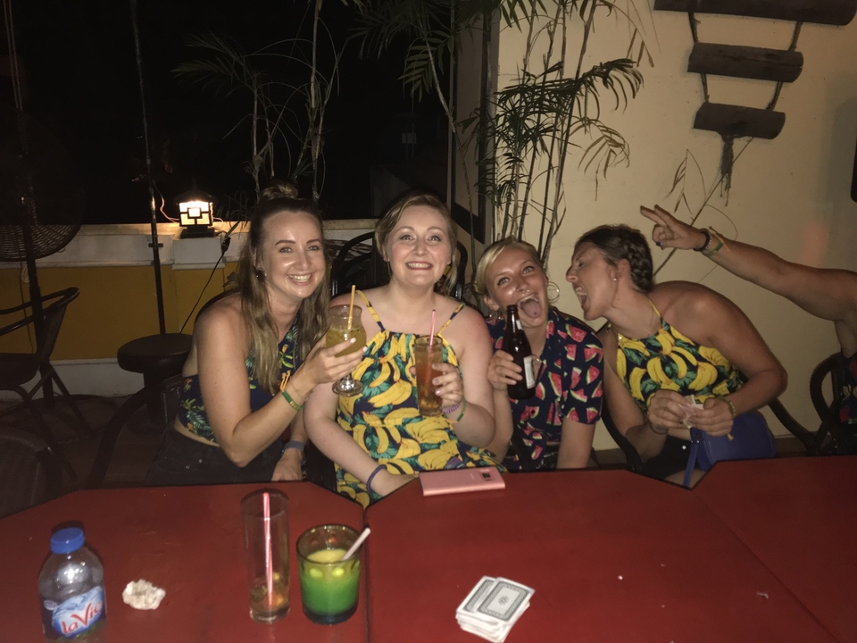 Un groupe de quatre personnes à une table, souriant et tenant des boissons.