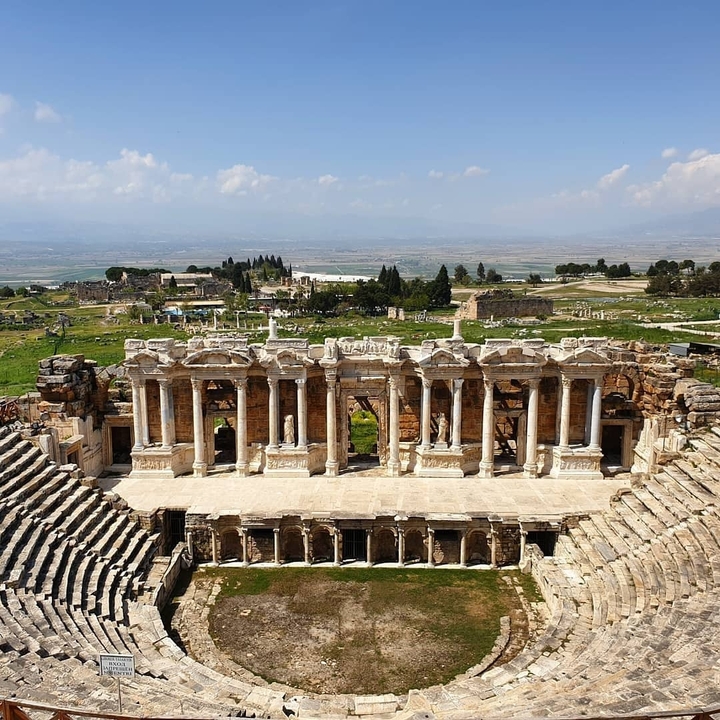 Ruines d'un amphithéâtre antique avec un décor de montagne.