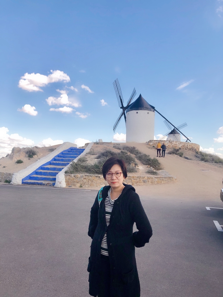 Une personne debout devant des moulins à vent sur une colline.