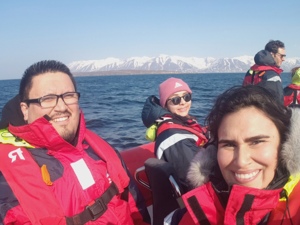 Group of people wearing life jackets on a boat with snowy mountains in the background.