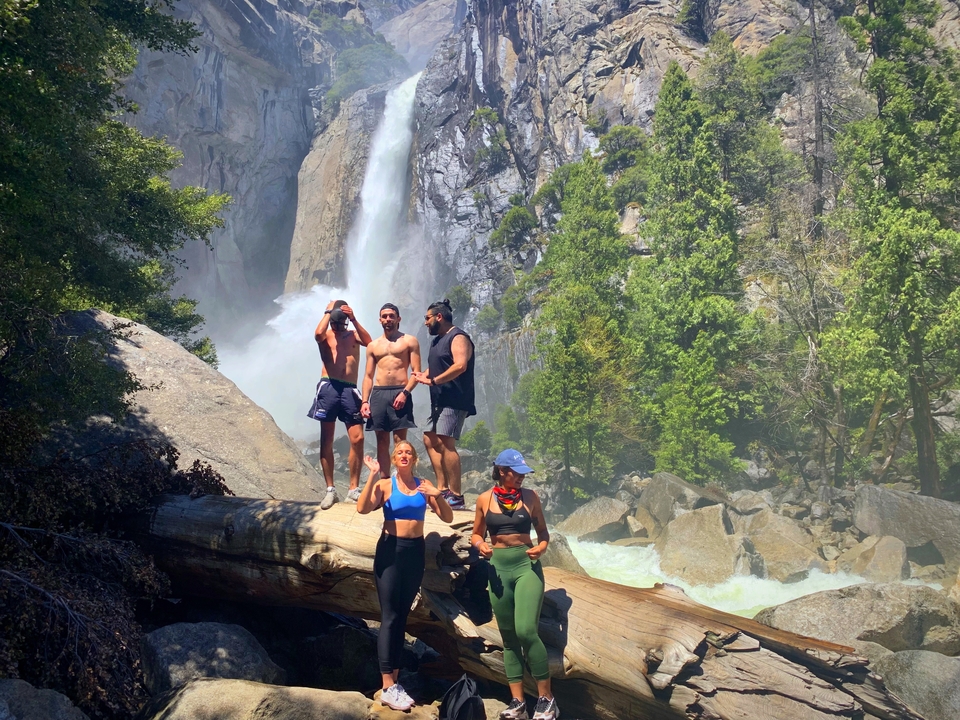 Groupe de personnes posant près d'une cascade dans une forêt luxuriante.