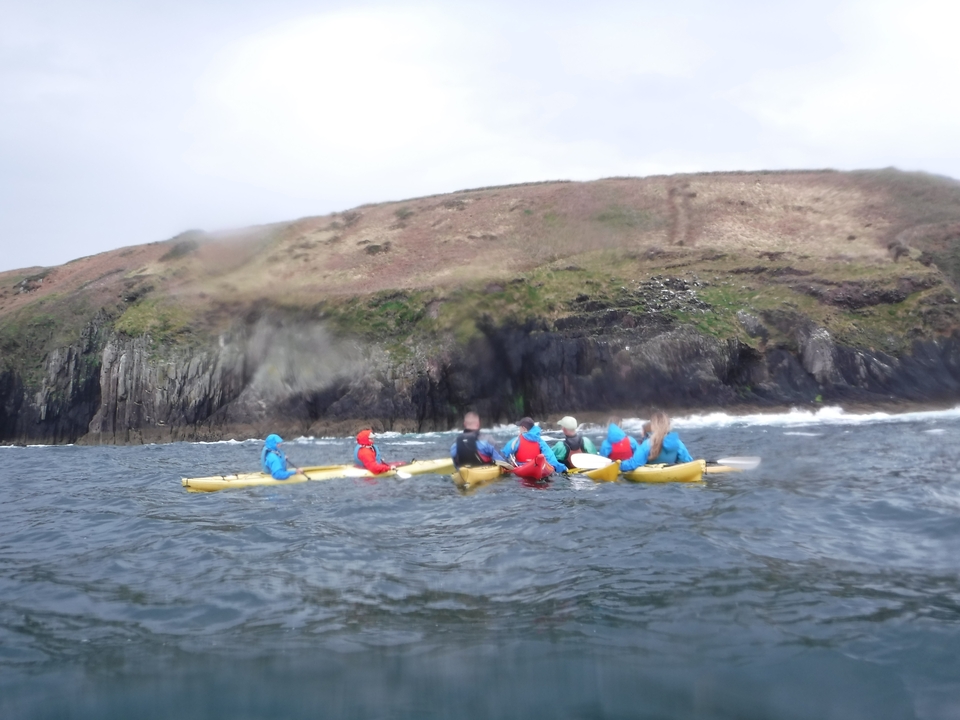 Kayak en groupe près d'une côte rocheuse.
