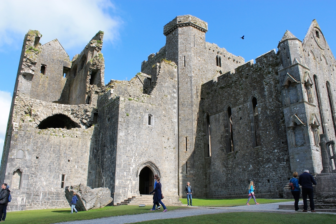 Ancien château de pierre avec des gens qui se promènent autour.
