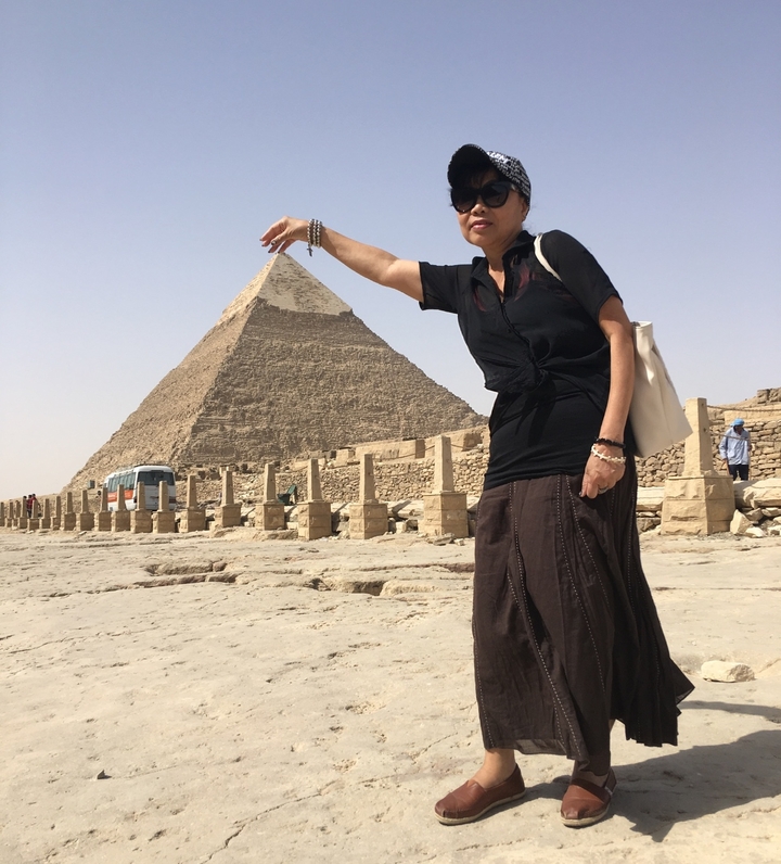 Personne posant avec une pyramide en arrière-plan.