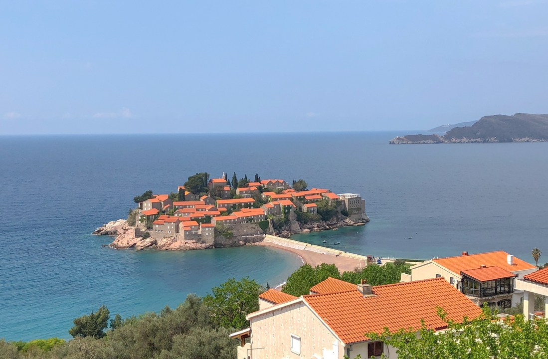 Île avec des bâtiments aux toits orange entourée d'une mer bleue.