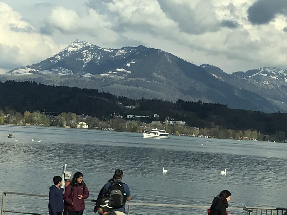 Des gens au bord d'un lac avec des montagnes en arrière-plan.