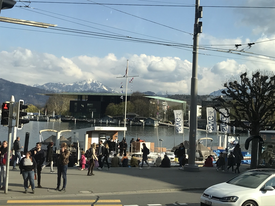 Des gens près d'un lac avec des bateaux et des montagnes enneigées.