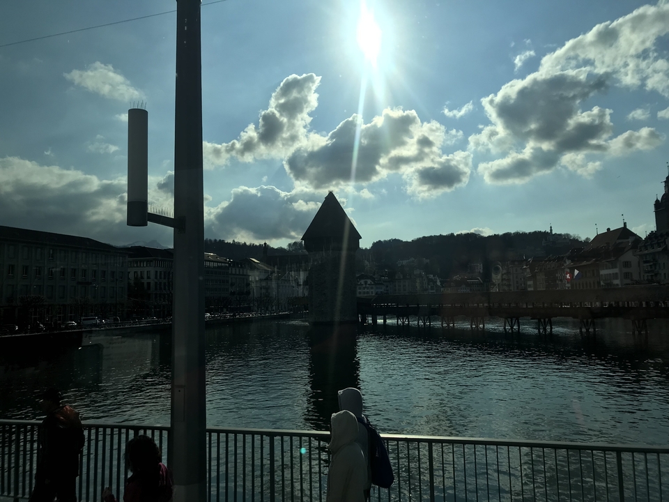 Scène en contre-jour d'un pont couvert au-dessus d'une rivière avec des montagnes.