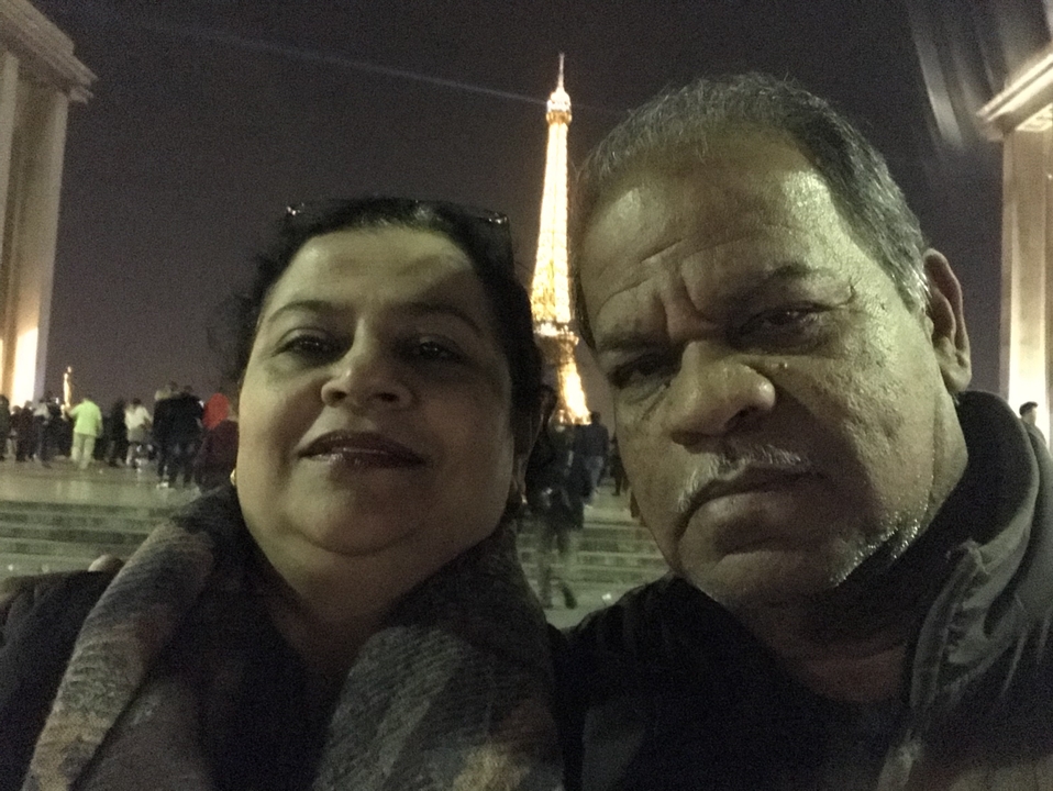Un couple prenant un selfie devant la tour Eiffel la nuit.