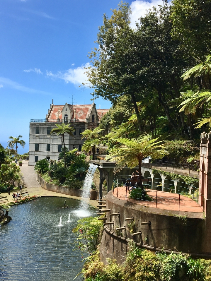 Des gens qui profitent d'un jardin avec une cascade et un vieux bâtiment.