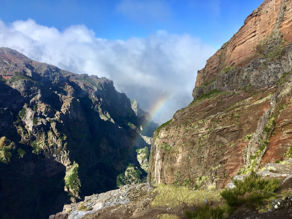 Paysage montagneux majestueux avec un arc-en-ciel visible.