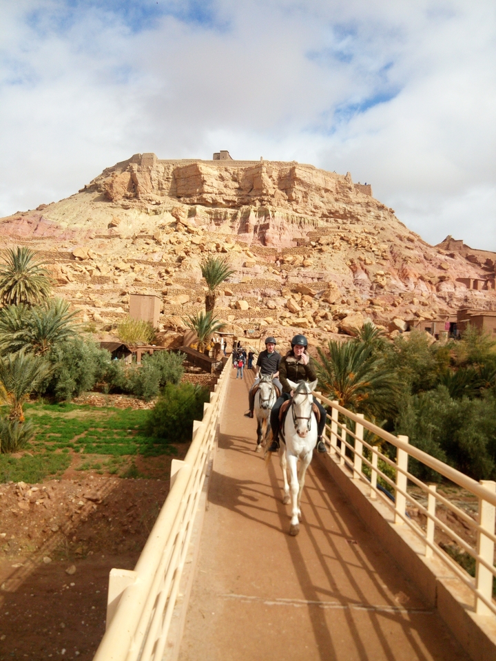 Cavaliers traversant un pont pittoresque dans une oasis du désert.
