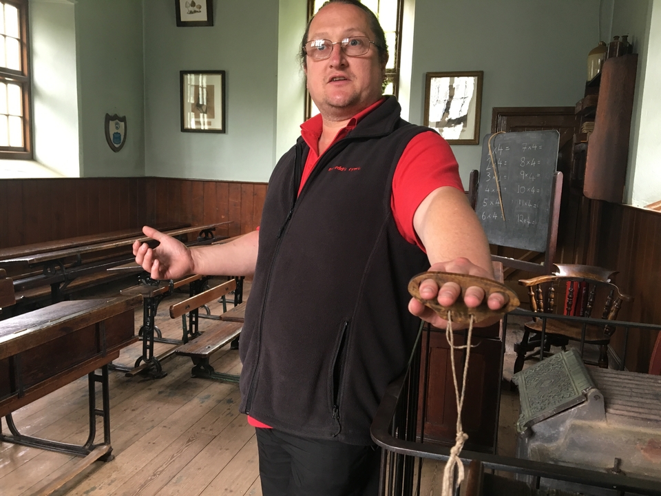 Personne démontrant un outil dans un cadre de salle de classe historique.