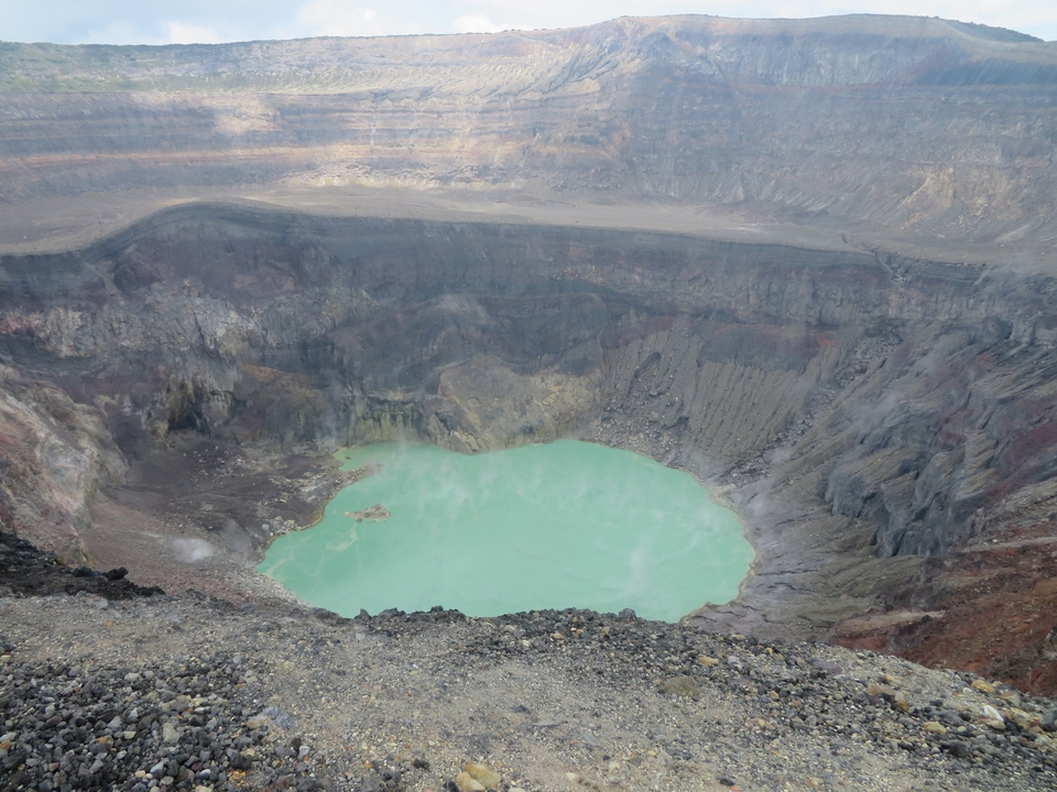 Cratère volcanique avec un lac turquoise au fond.