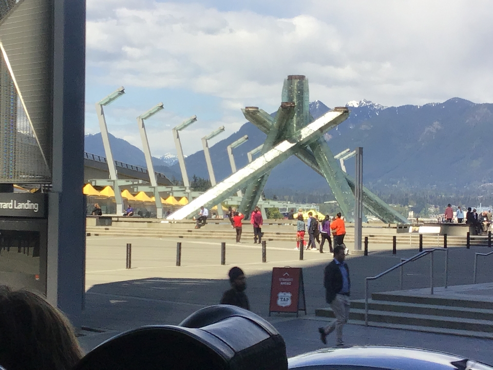 Place publique avec une grande sculpture de verre et des montagnes en arrière-plan.