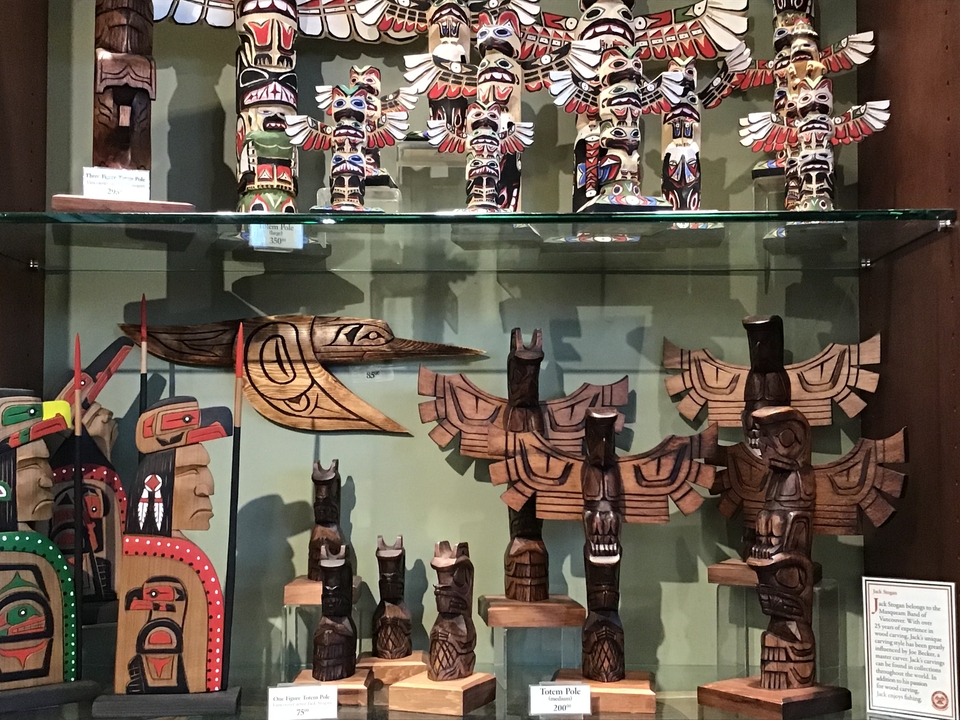 Exposition de mâts totémiques et d'art indigène dans une vitrine.