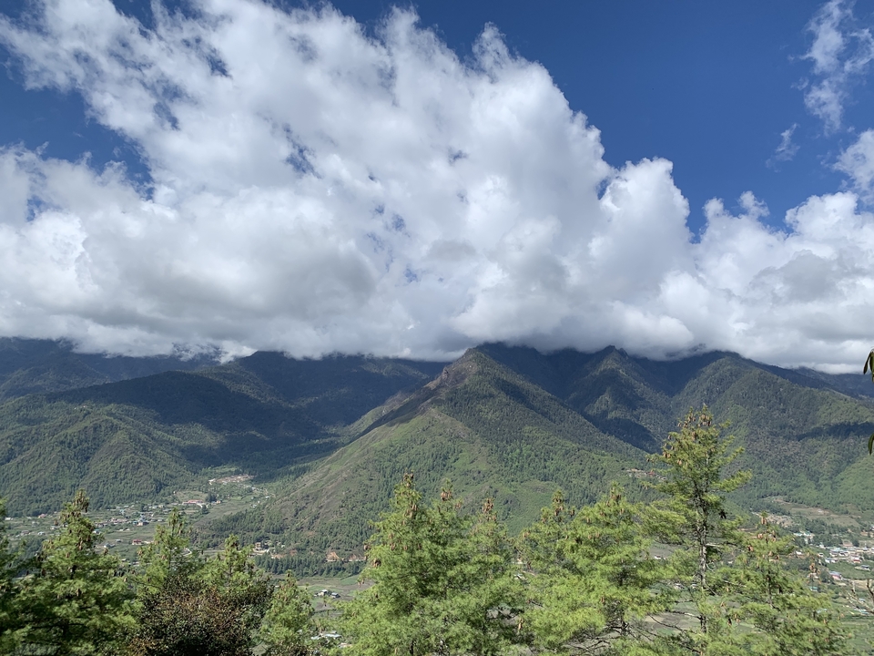 Vue panoramique de montagnes verdoyantes et de ciel nuageux.