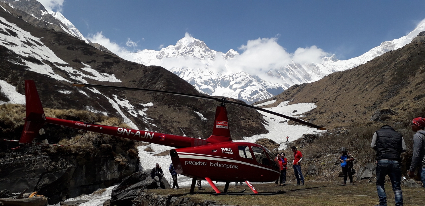 Un hélicoptère et des personnes dans un paysage montagneux enneigé.