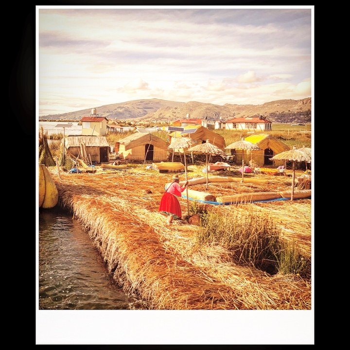 Floating reed homes with a person among them on a lake.