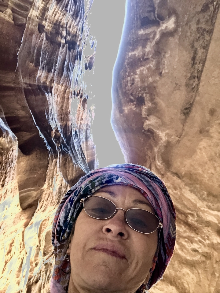 Personne dans un canyon étroit avec un ciel lumineux au-dessus.