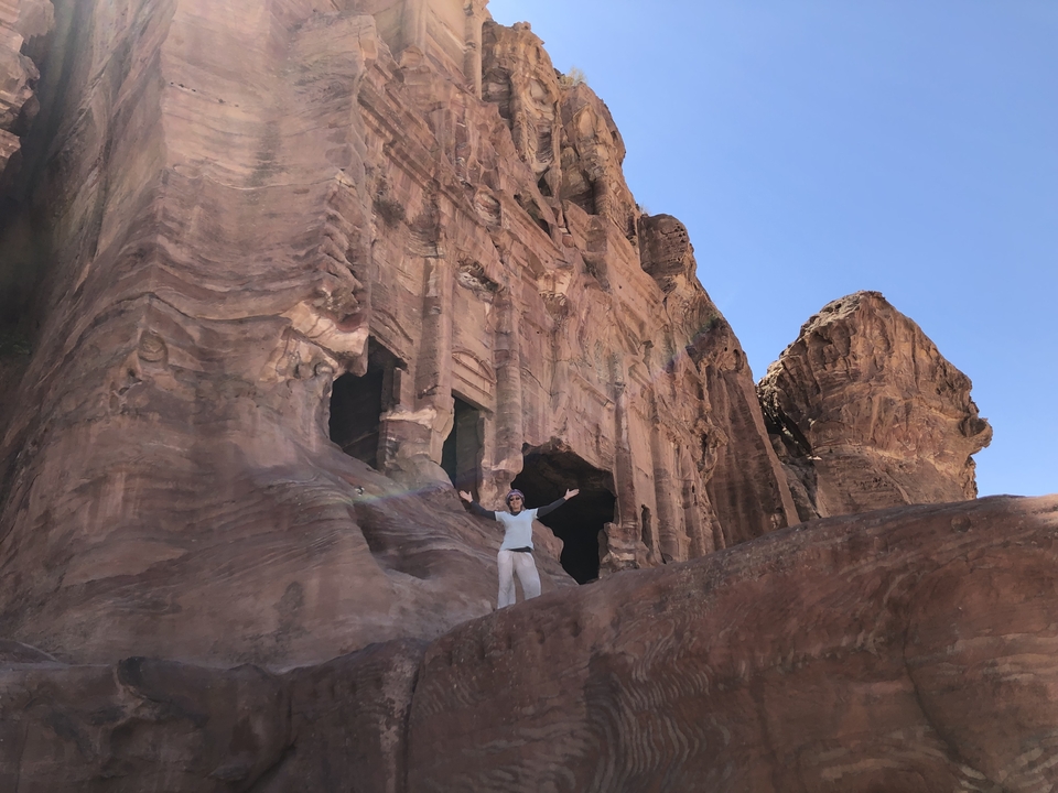 Personne posant devant une architecture ancienne taillée dans la roche.