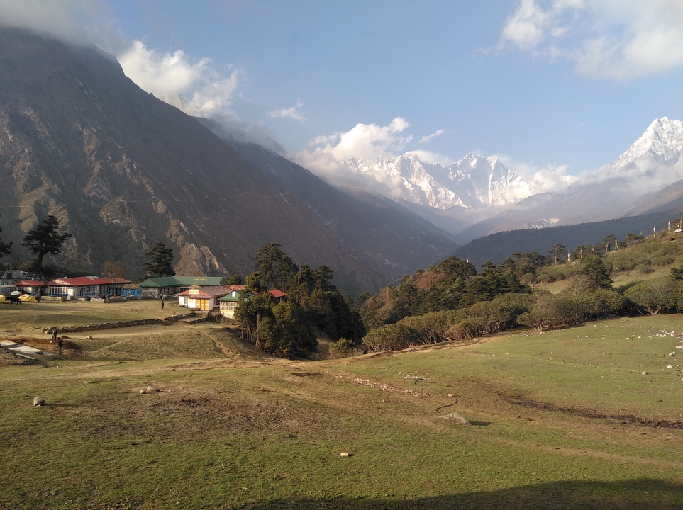 Vue champêtre d'une vallée avec des montagnes enneigées au loin.