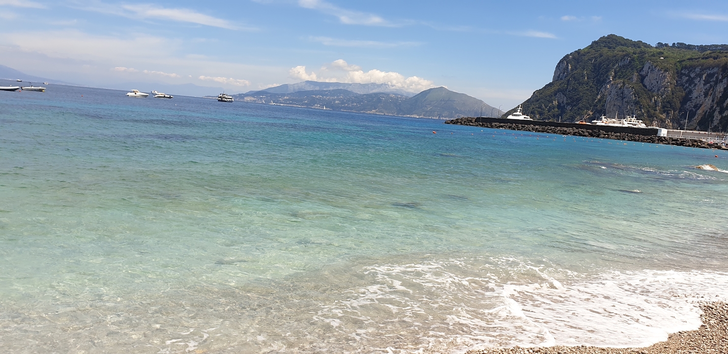 Plage aux eaux claires et aux montagnes lointaines.