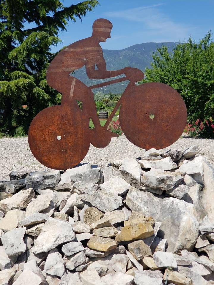 Une sculpture en métal d'un cycliste sur un terrain rocheux.