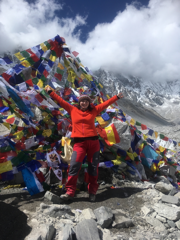 Personne joyeuse avec des drapeaux de prière dans un lieu montagneux de haute altitude.