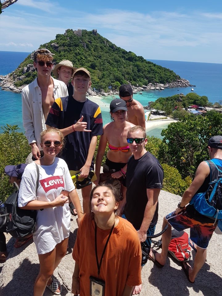 Group posing on a rocky outcrop with the sea in the background.