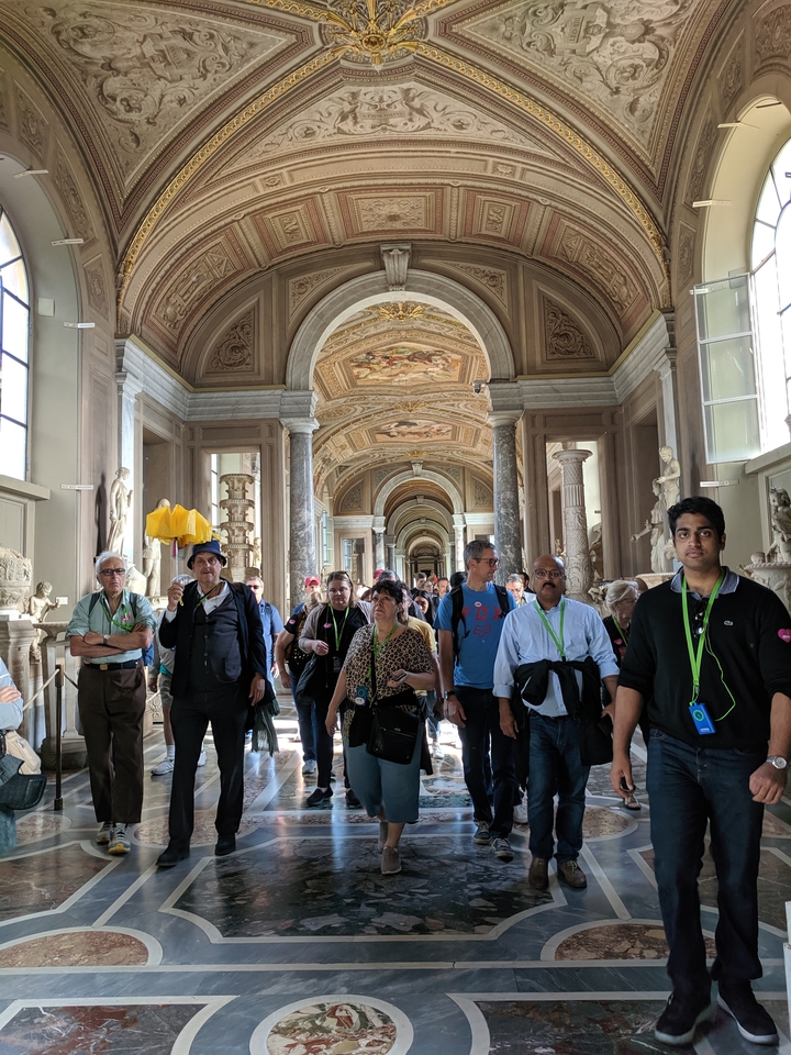 Groupe de touristes marchant dans un couloir orné.