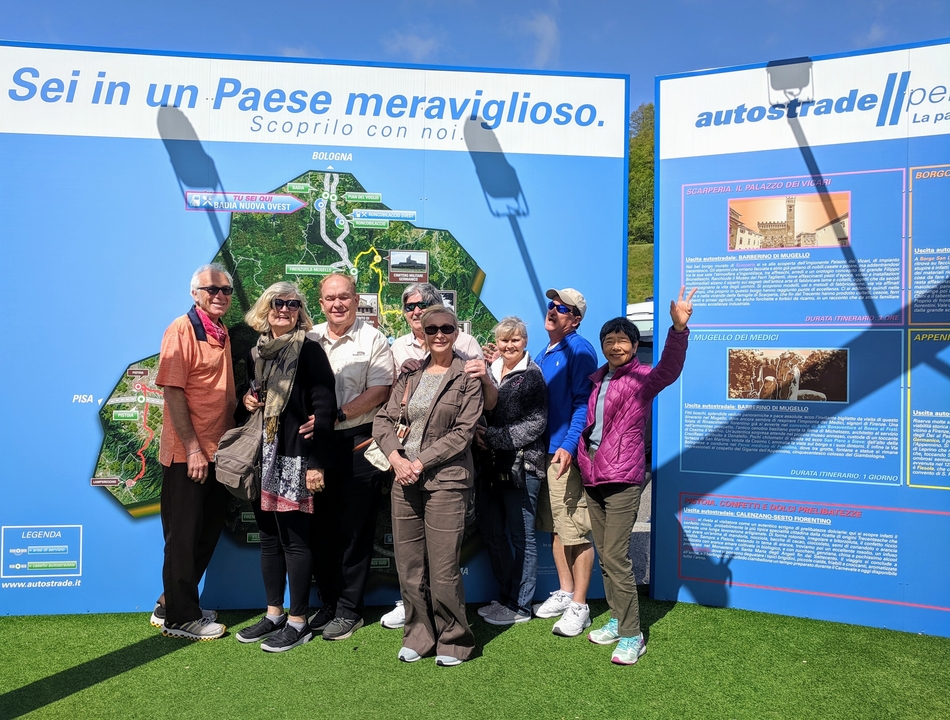 Groupe de personnes debout devant un panneau d'affichage de carte en Italie.