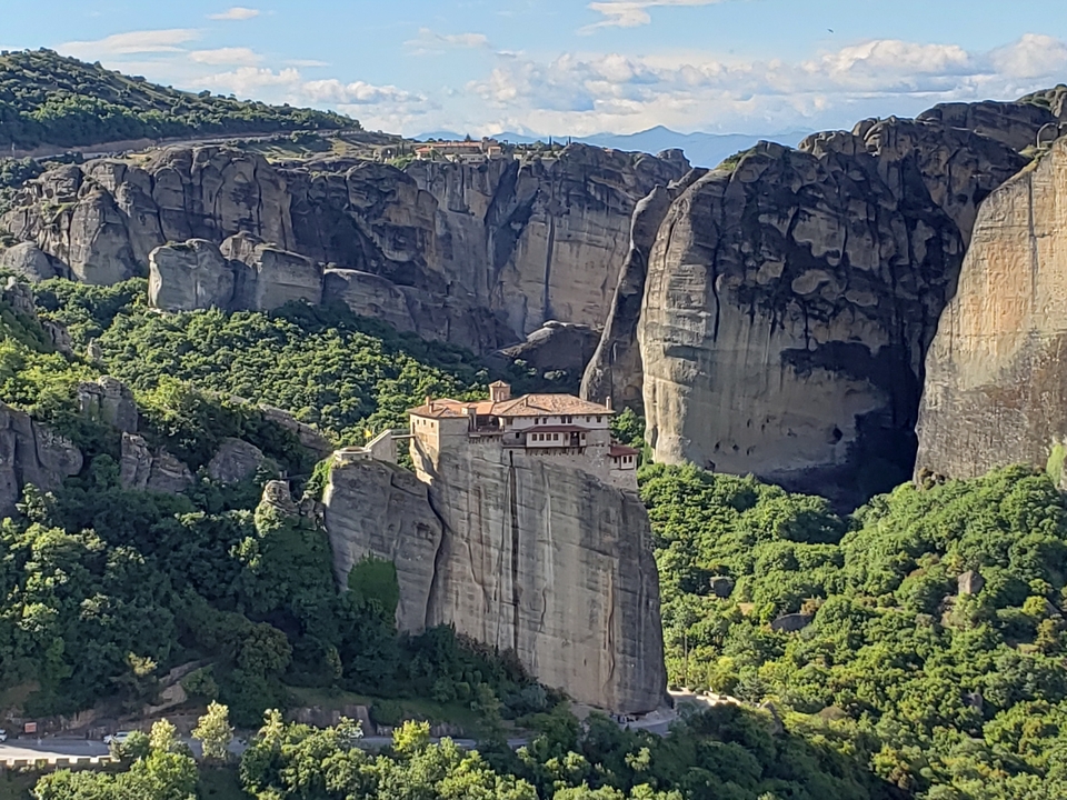 Vue aérienne d'un monastère perché sur une formation rocheuse.
