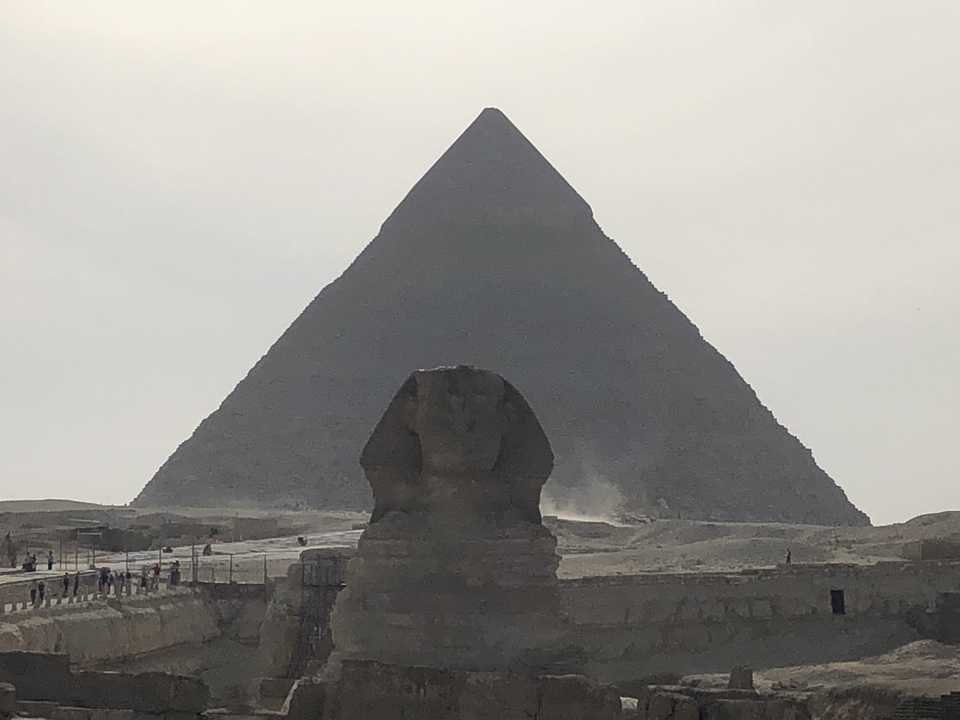 Sphinx et Grande Pyramide de Gizeh sous un ciel gris.