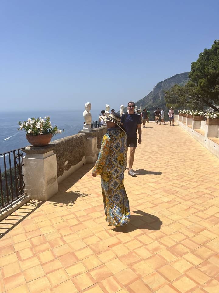 Personne qui pose sur une terrasse avec d'autres qui passent.
