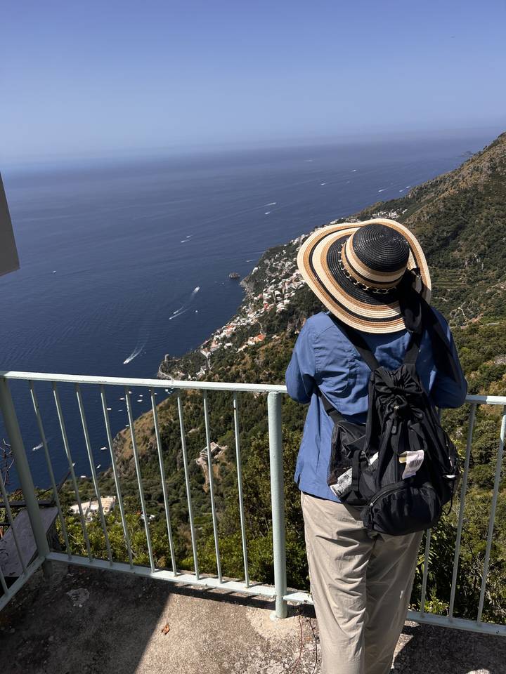 Personne appuyée sur une rambarde, regardant un paysage côtier.